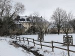 Eingezäunte Wiese im Schnee, im Hintergrund das Wasserschloss Alme